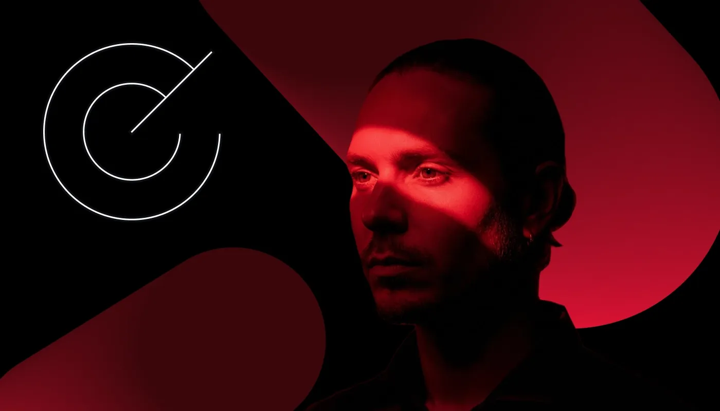 A man is looking in front of him; a red light is cast across his eyes.